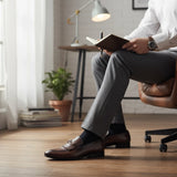 ARQS.PK 1708 brown leather loafers with metal bit detail worn by a man in a white shirt and grey trousers