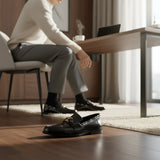 ARQS.PK 727 black leather loafers with gold hardware and monogram detailing worn by a man in a home office setting