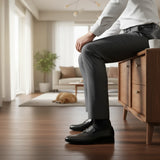 ARQS.PK men's black formal leather loafers with metallic strap detail worn with grey trousers in a modern living room