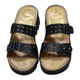 ARQS.PK black platform slide sandals with dual straps, cut-out details, metallic studs, and reflex-zone footbed.