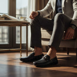 ARQS.PK men's black textured leather loafers with metal horsebit detail worn by a man in a business-casual setting.